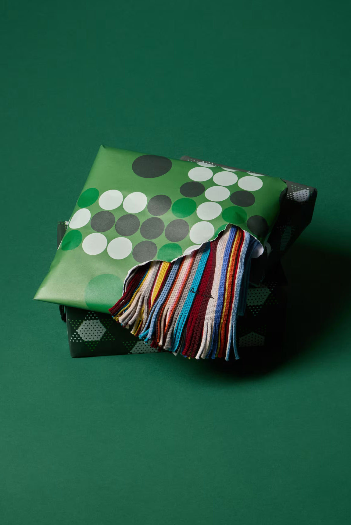 Green fabric bag with colorful tassel on a green background