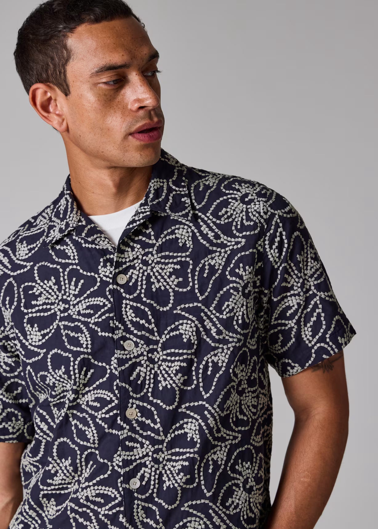 Man wearing a navy patterned shirt against a gray background