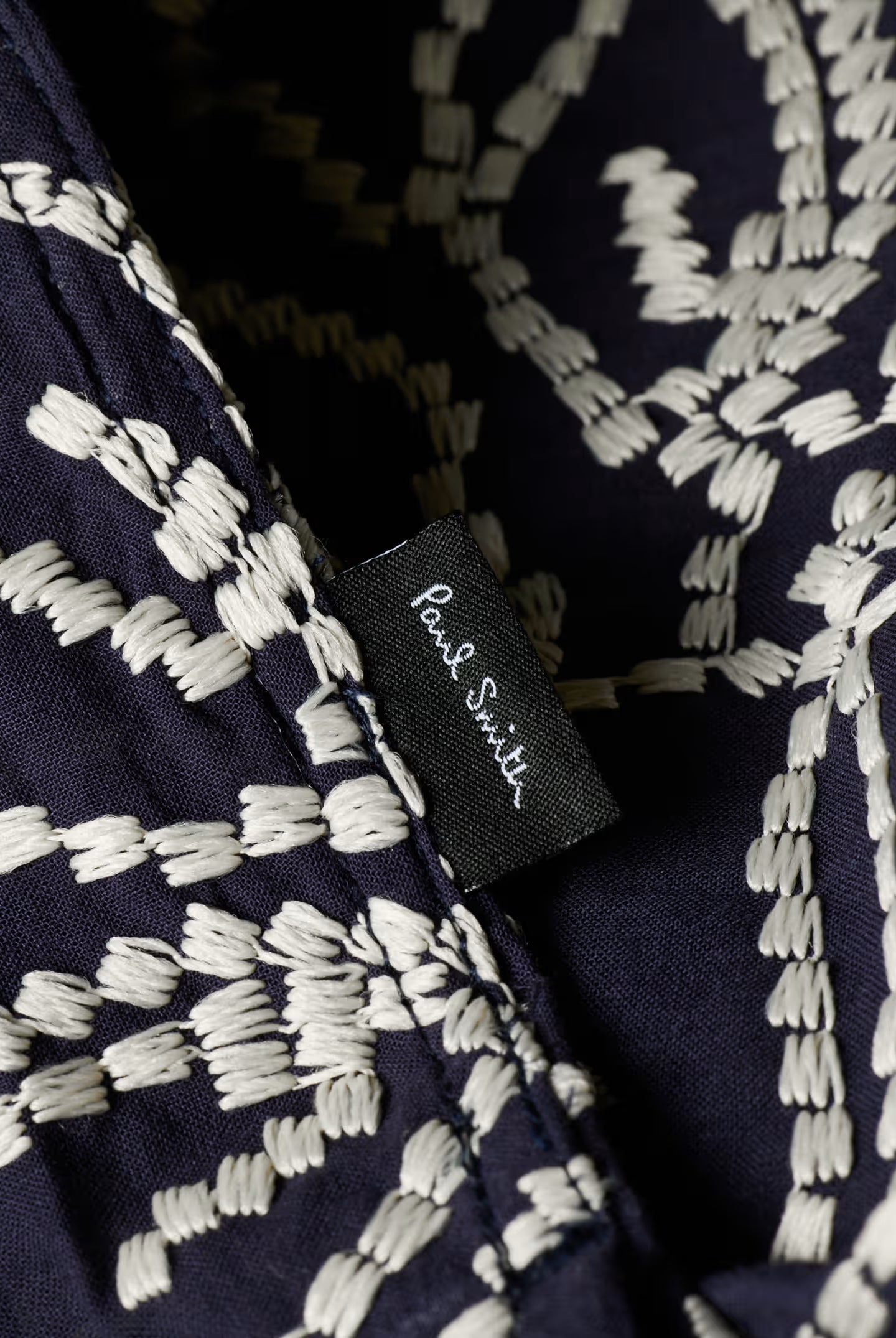 Navy blue fabric with white geometric pattern and 'Paul Smith' label.