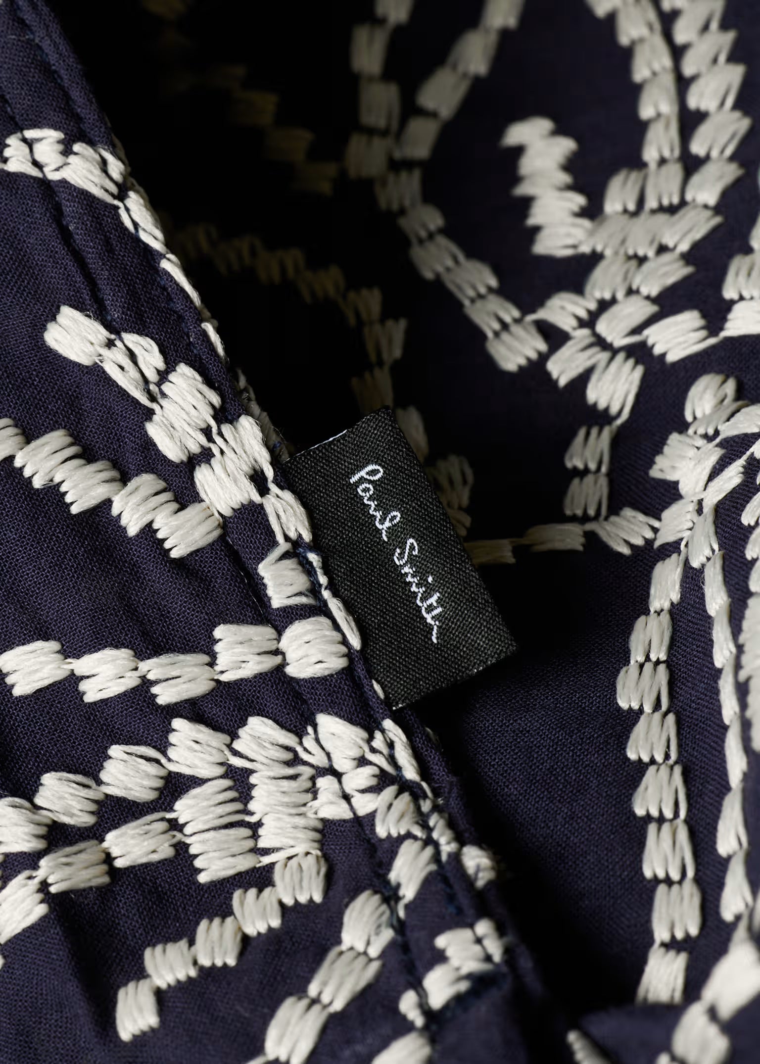 Navy blue fabric with white geometric pattern and 'Paul Smith' label.
