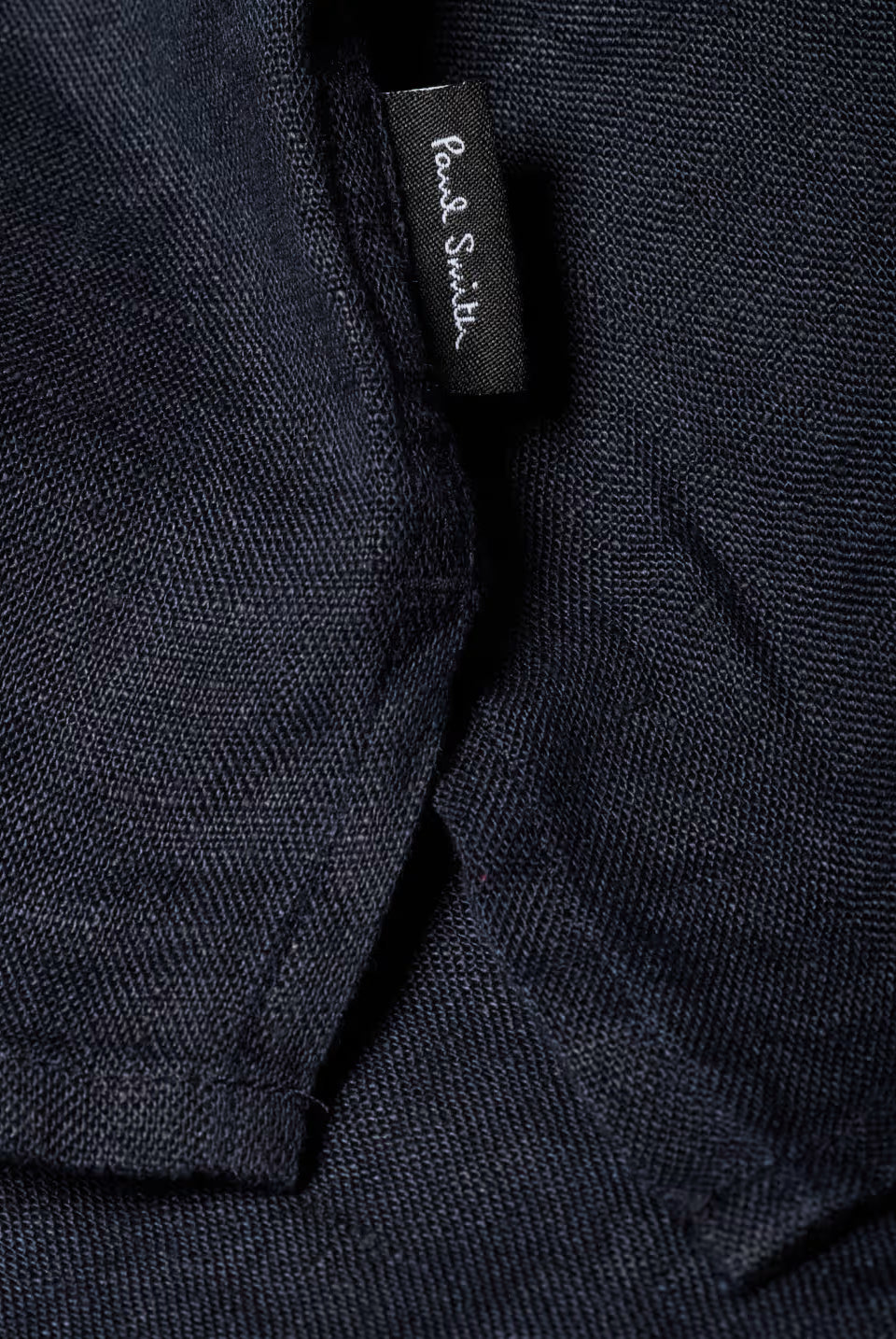 Close-up of a dark fabric with a brand label on a black background