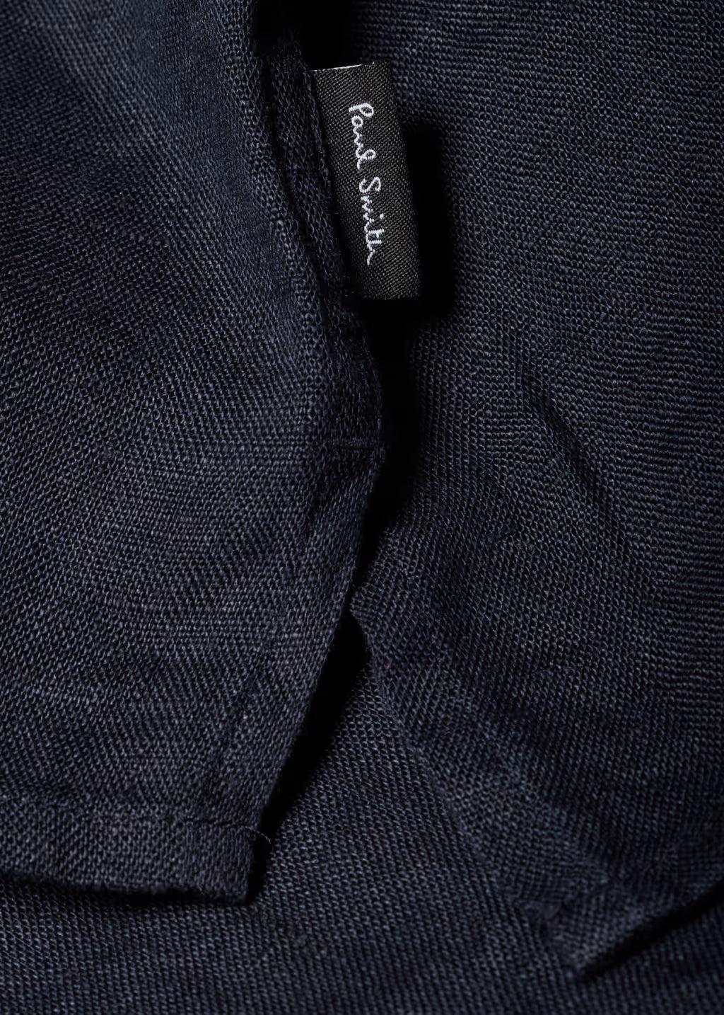 Close-up of a dark fabric with a brand label on a black background