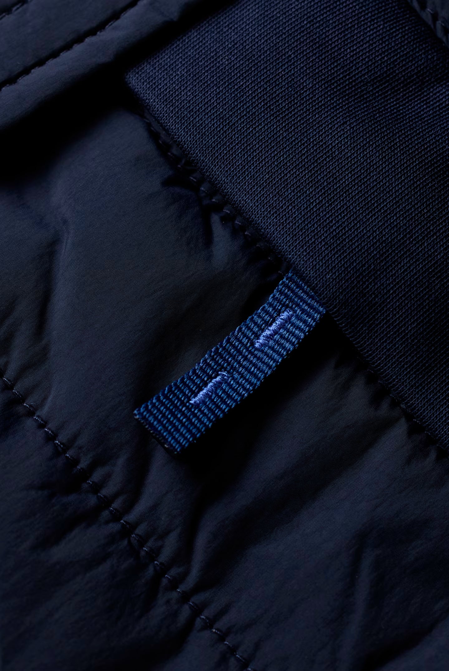 Close-up of a dark blue fabric with a brand label on a black background