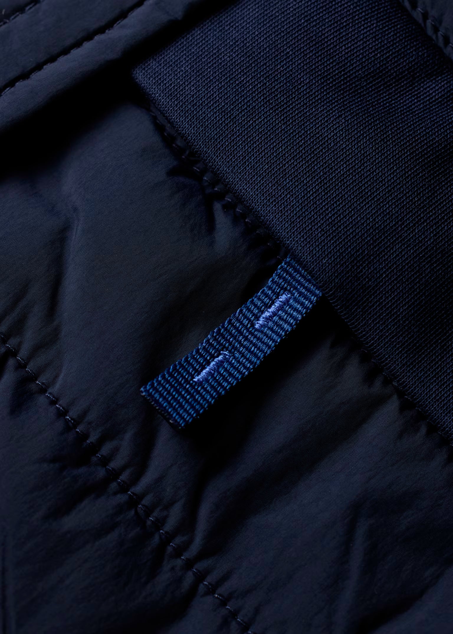 Close-up of a dark blue fabric with a brand label on a black background