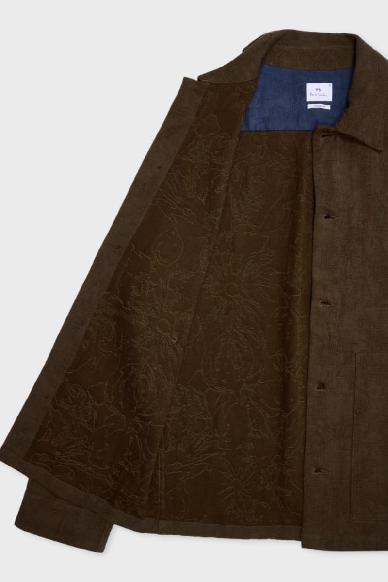 A dark brown textured overshirt with a subtle tonal floral jacquard pattern, shown open to reveal a blue inner lining and a white brand label inside the collar.