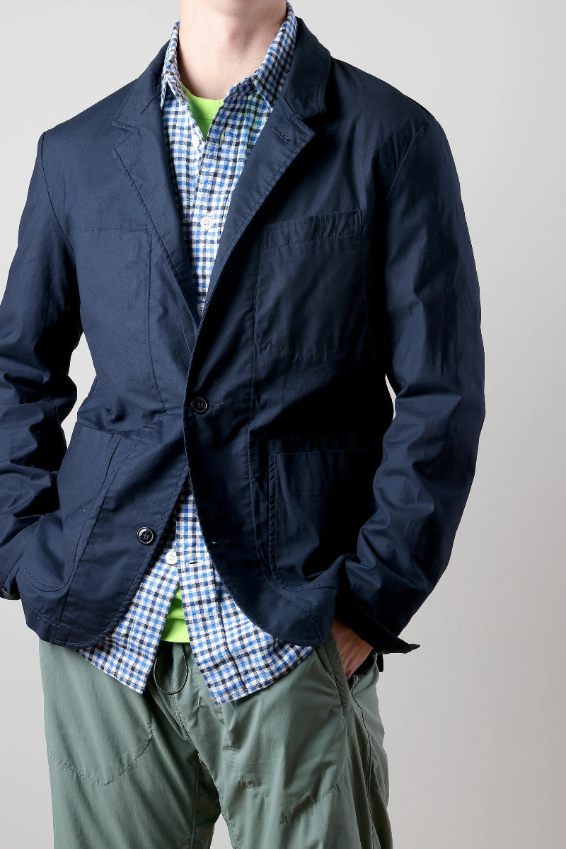 Person wearing a navy jacket over a checkered shirt with a plain background