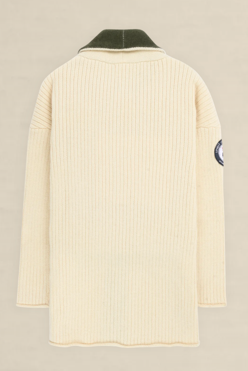 A cream-colored ribbed knit sweater shown from the back, featuring a dark olive green collar and a circular patch on the left sleeve, set against a light beige background.