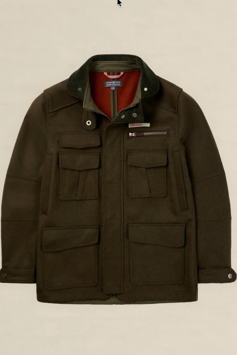 A dark olive green waxed cotton jacket with a corduroy collar, multiple front flap pockets, and a red inner lining, shown against a solid light beige background.