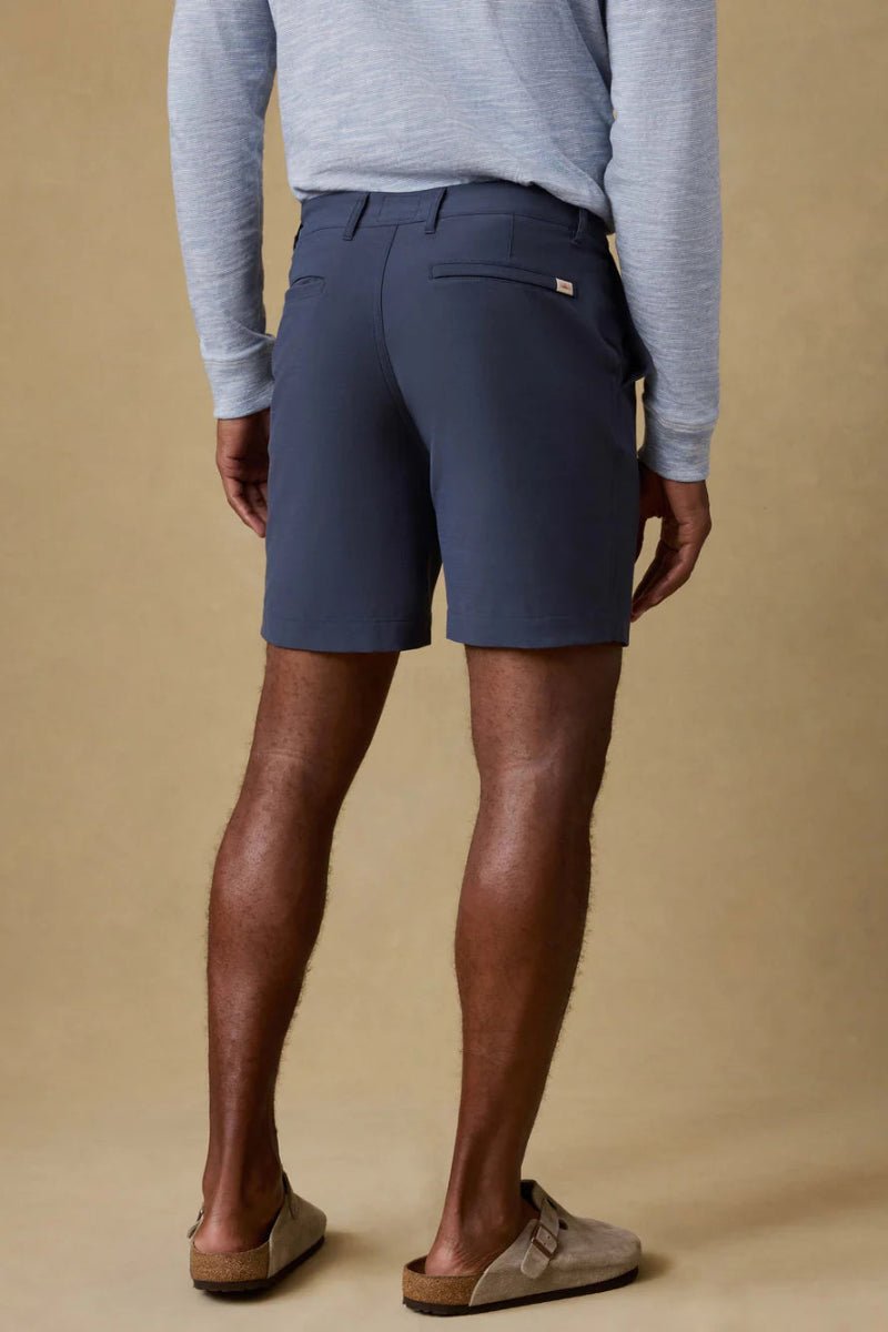 Person wearing navy shorts and a gray sweater on a beige background