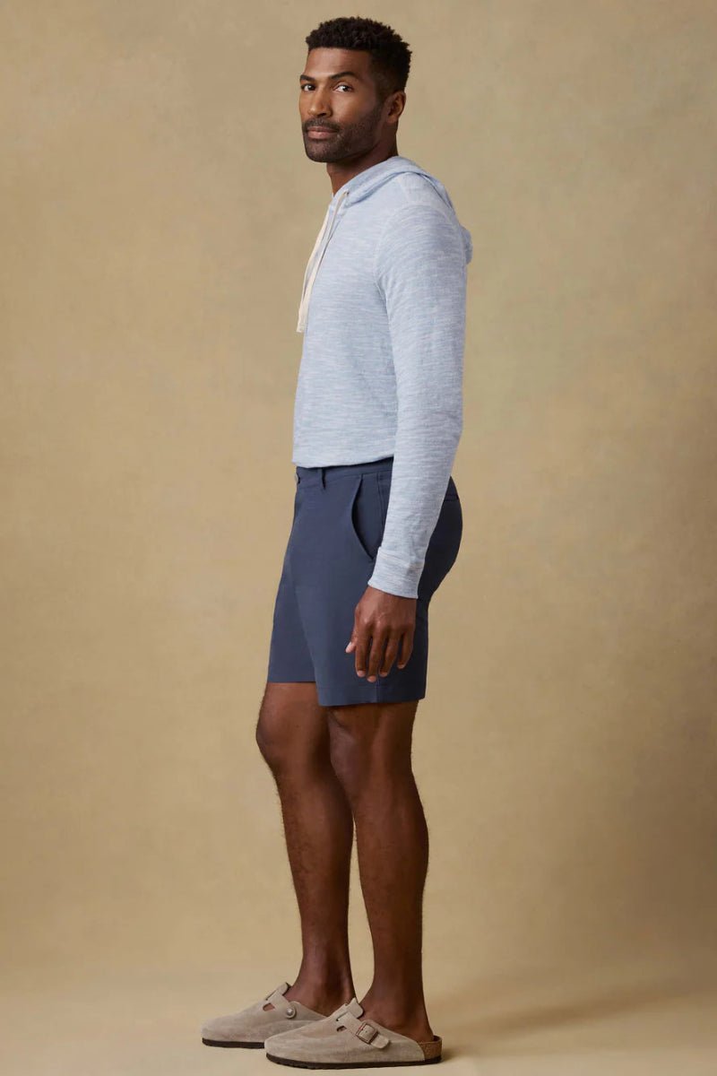 Man wearing a light blue hoodie and dark shorts on a beige background