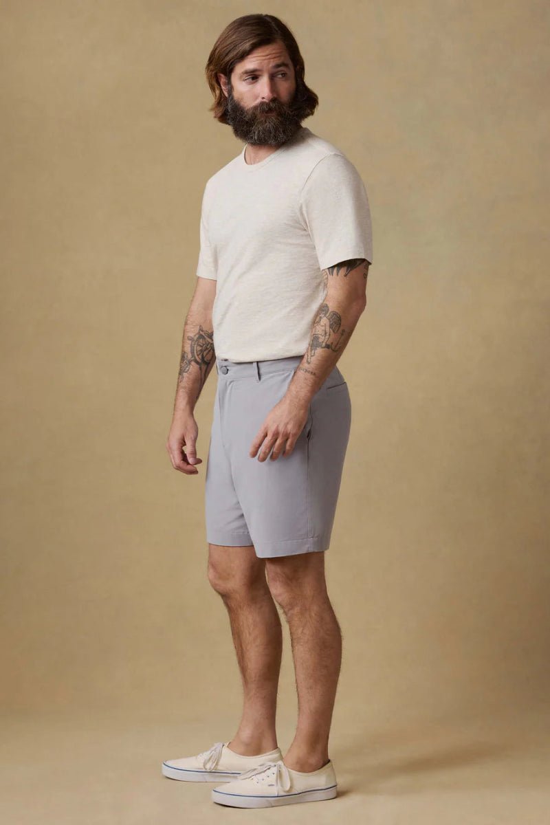 Man wearing a white t-shirt and light gray shorts against a beige background