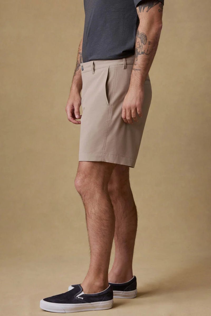 Man wearing beige shorts and black shoes on a beige background