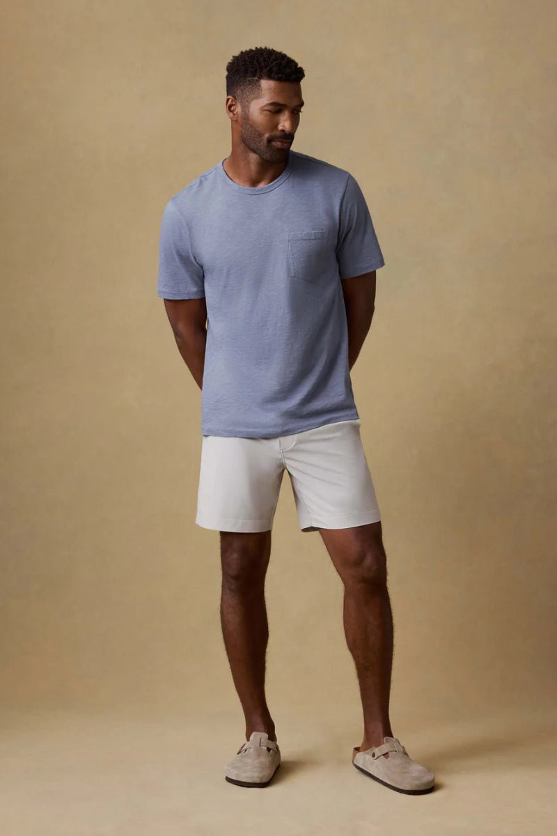 Man wearing a blue t-shirt and white shorts against a beige background