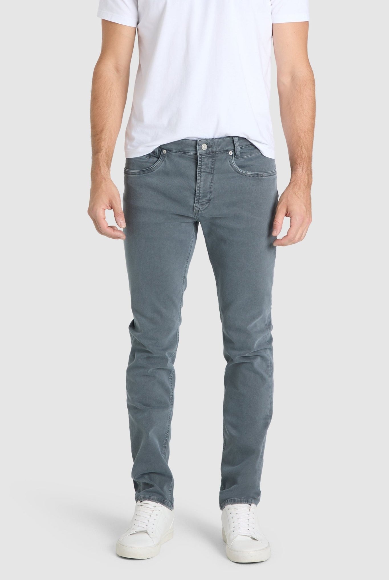 Person wearing gray jeans and a white t-shirt on a plain background