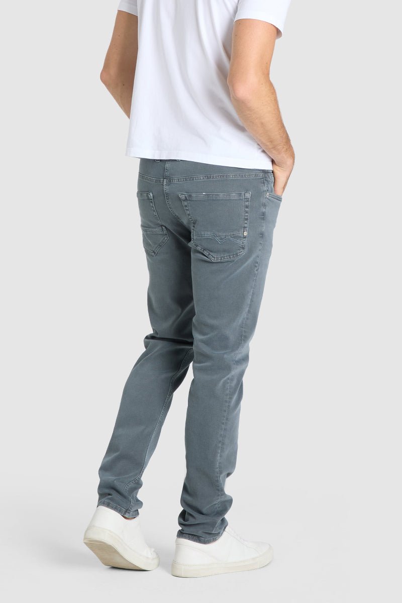 Person wearing gray jeans and white sneakers on a plain background