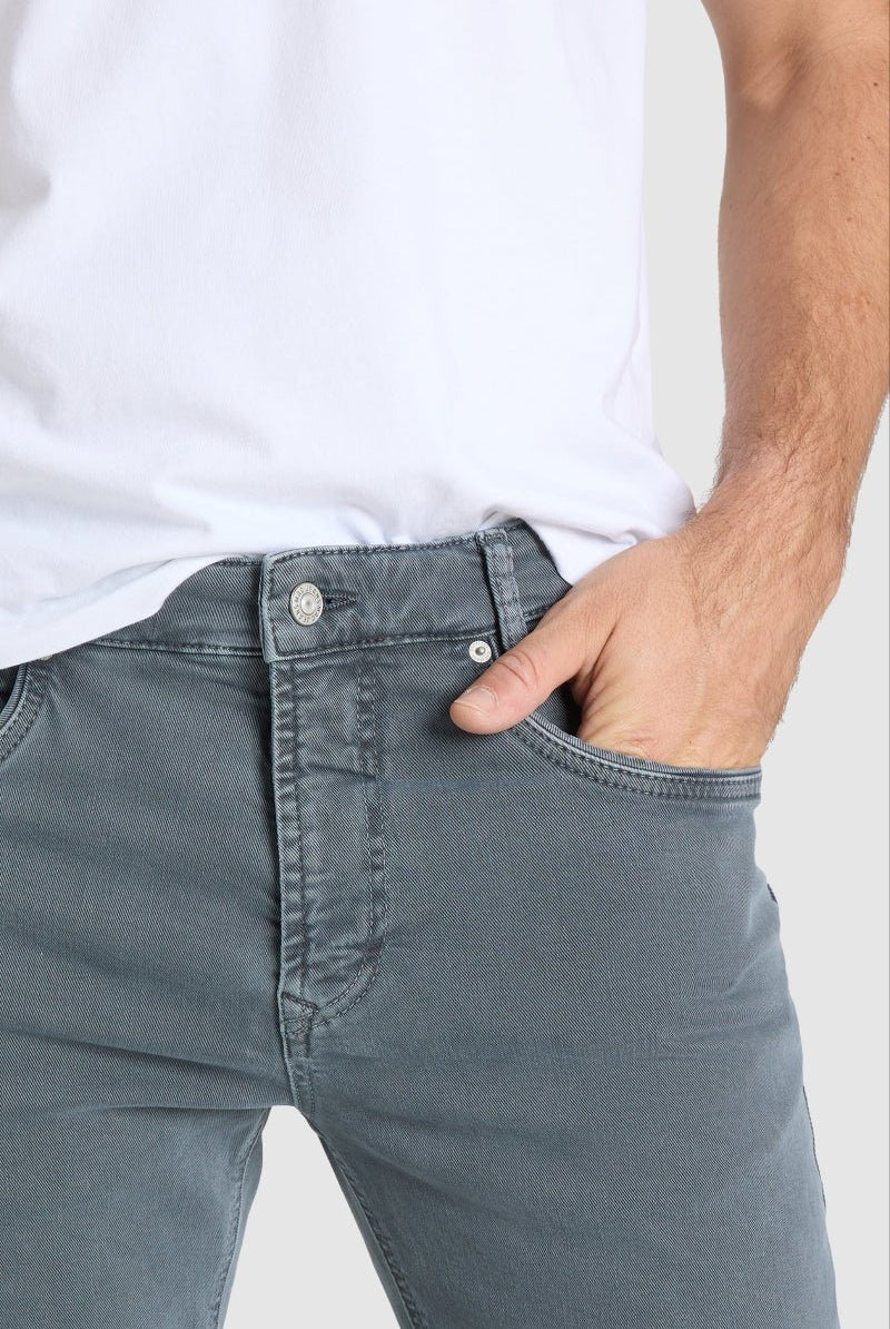 Person wearing gray jeans and a white shirt on a plain background