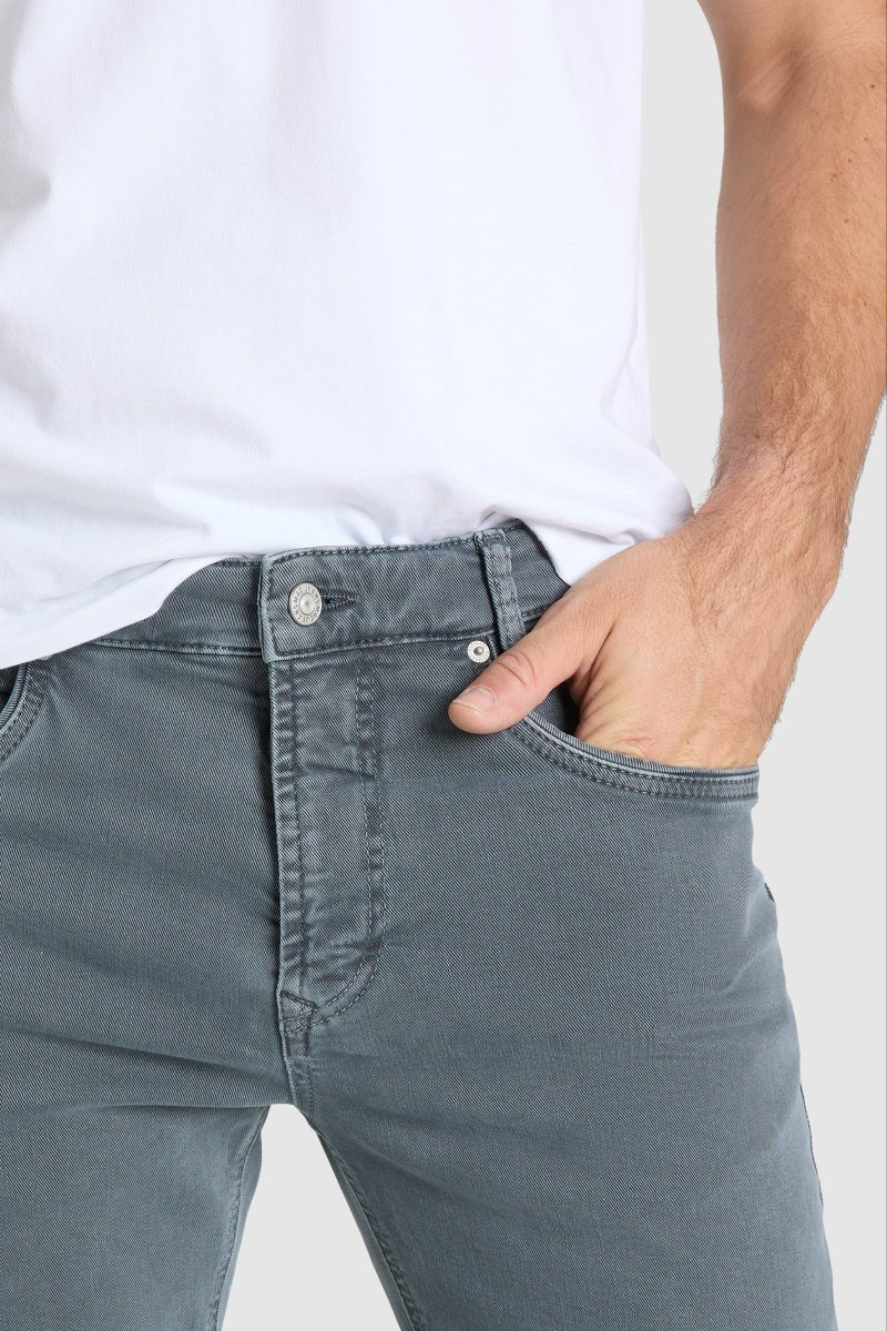 Person wearing gray jeans and a white shirt on a plain background