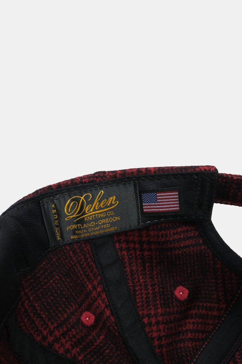 Close-up of a red and black checkered jacket with a brand label on a white background
