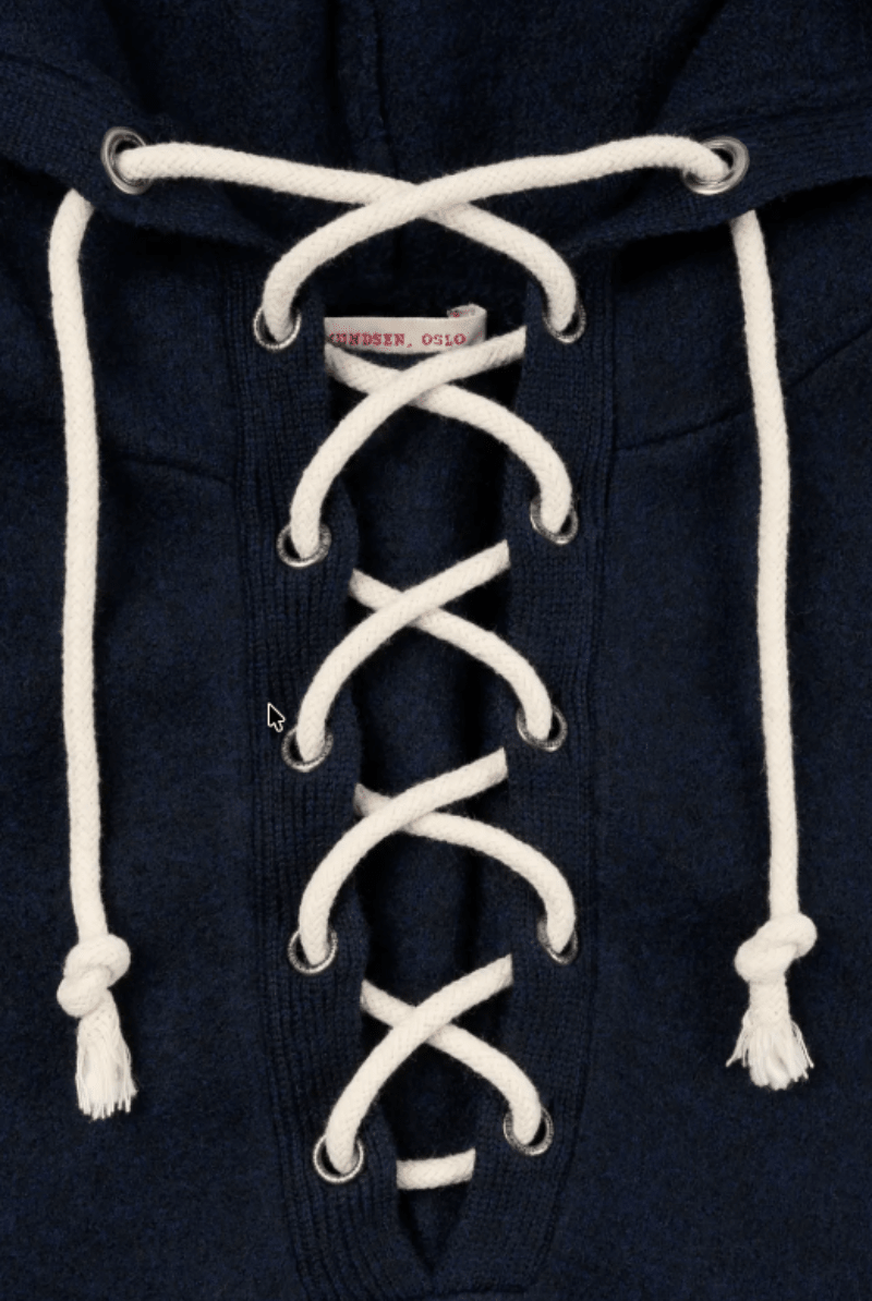 Close-up of a navy blue hooded sweatshirt with white laces threaded down the front and white drawstrings at the hood.