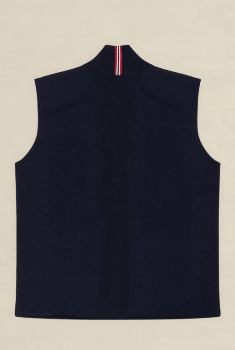 A sleeveless navy blue knit vest shown from the back, featuring a high mock neck with a vertical red, white, and blue striped accent at the collar, laid flat on a light beige background.