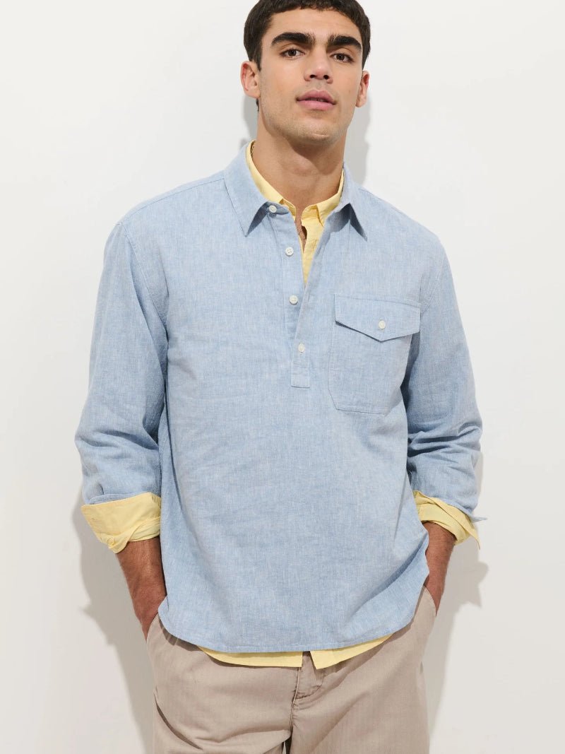 Man wearing a light blue shirt with yellow cuffs and collar against a white background