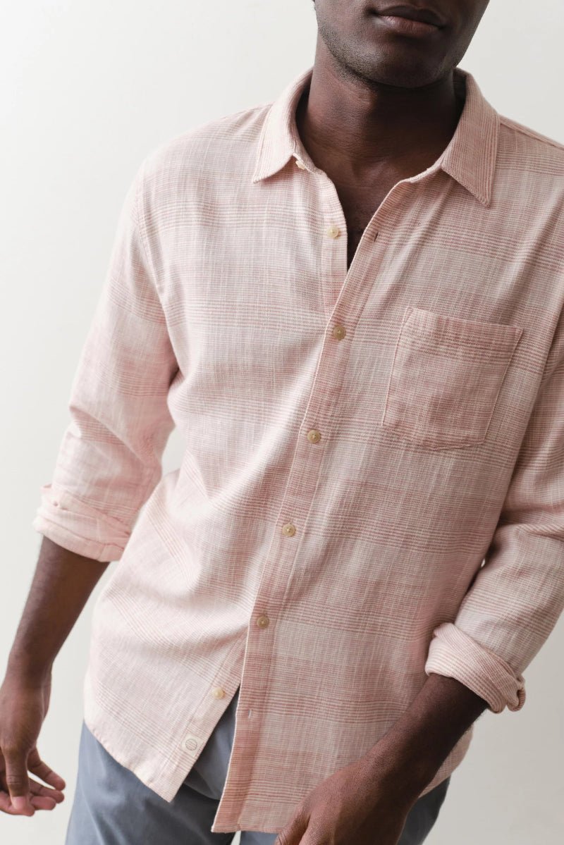Man wearing a light pink checkered shirt against a plain background