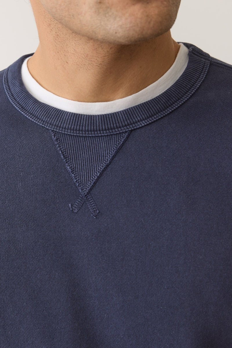 Navy blue sweatshirt with a white collar on a neutral background