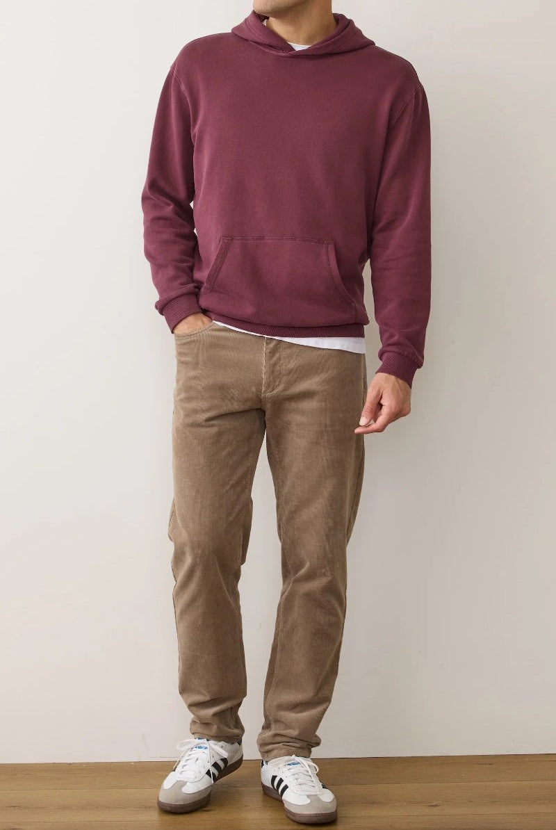 Person wearing a maroon hoodie, beige pants, and white sneakers against a plain background