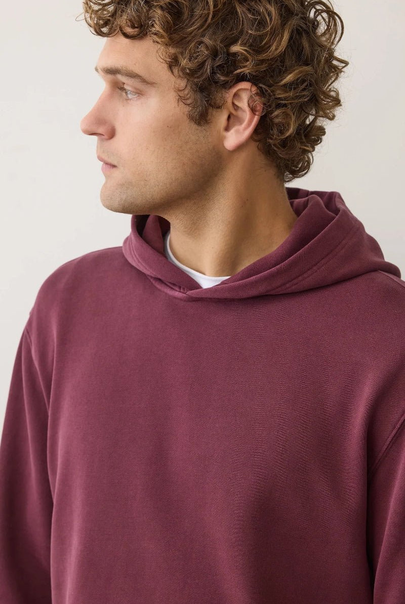 Man wearing a maroon hoodie against a plain background