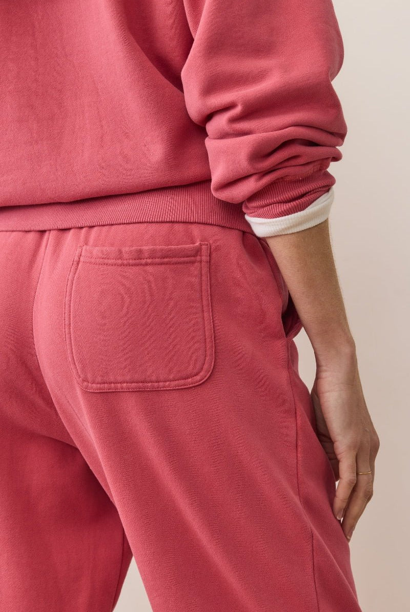 Person wearing a pink tracksuit with a neutral background