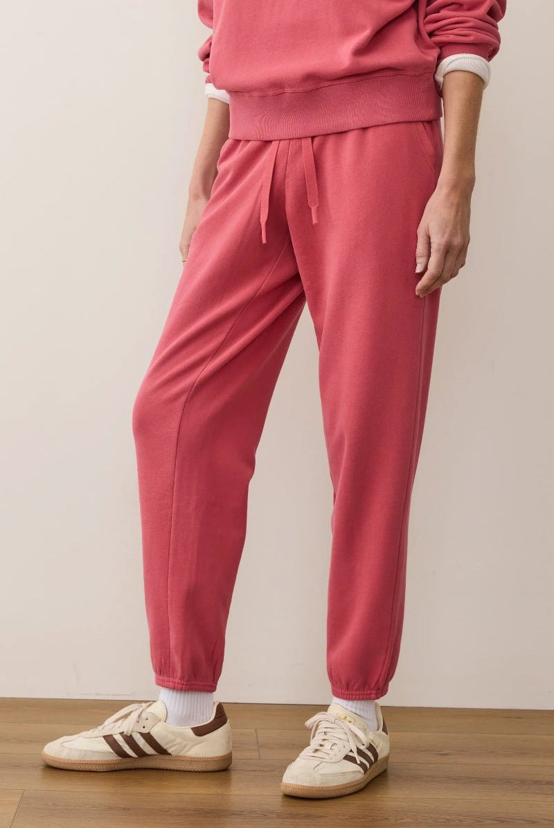 Person wearing a pink tracksuit with white sneakers on a plain background