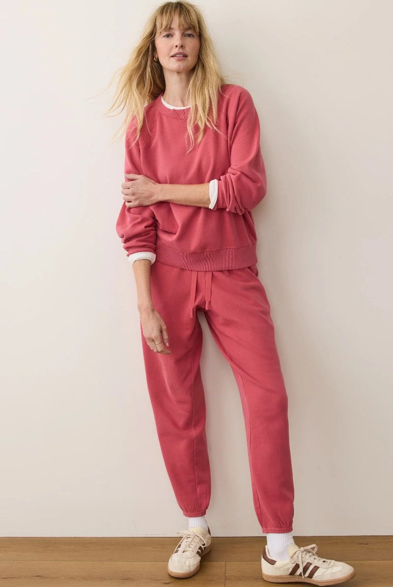 Person wearing a pink outfit with white sneakers against a plain background