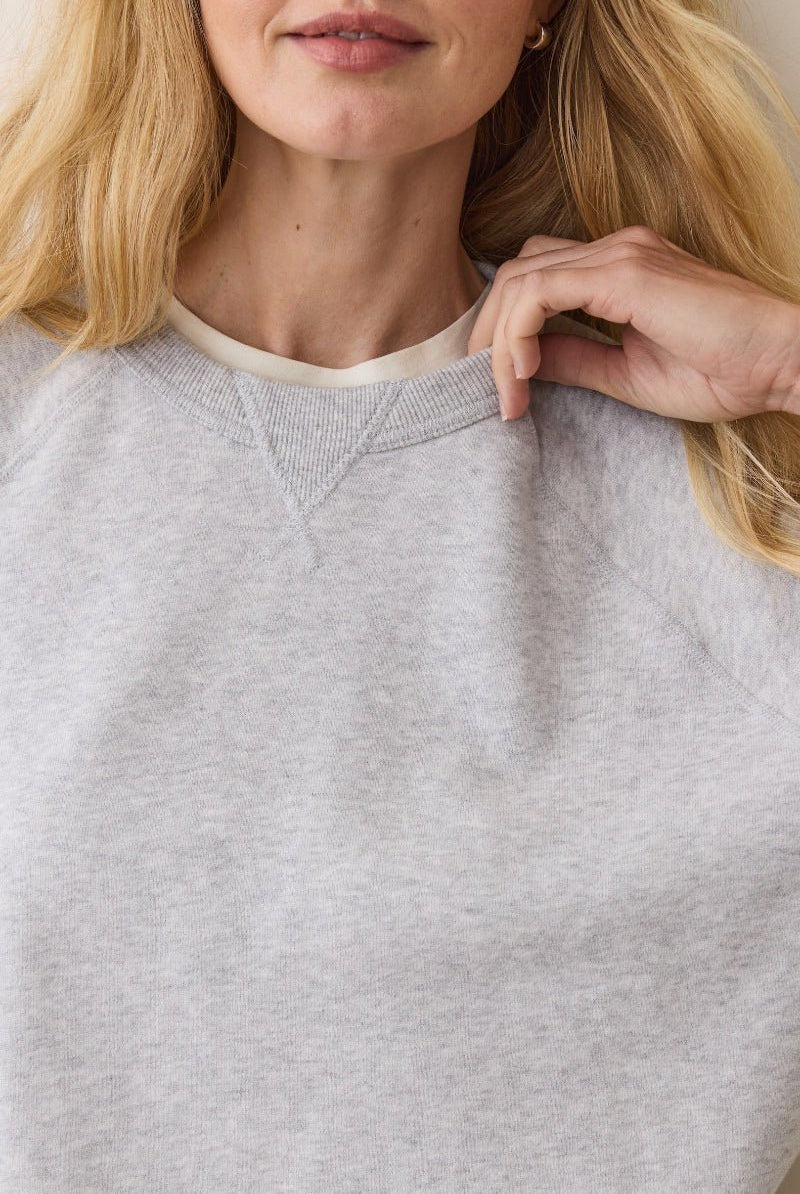 Person wearing a gray sweatshirt with a neutral background