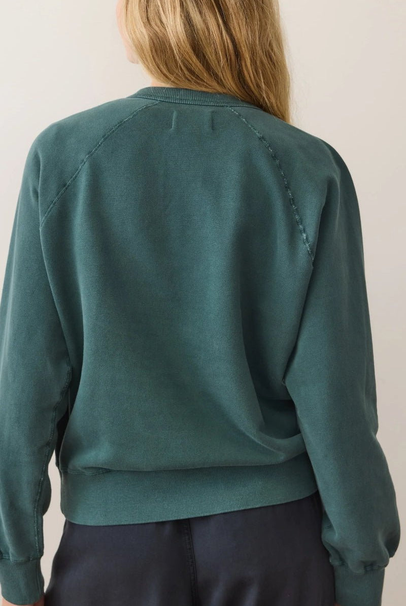 Person wearing a teal sweater against a plain background