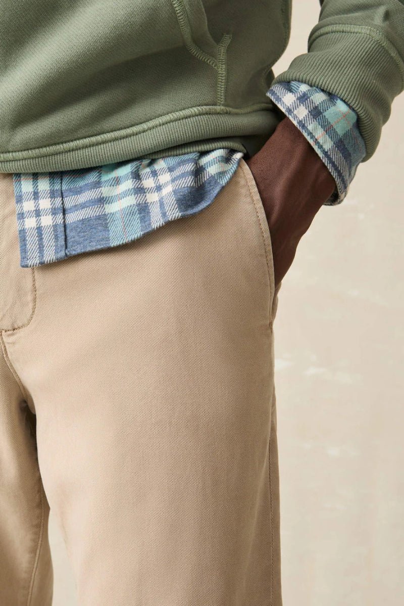 Person wearing a green fleece jacket over a plaid shirt with beige pants on a neutral background