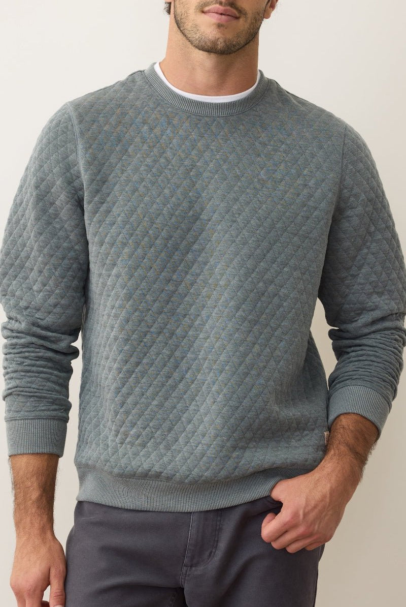 Man wearing a textured blue sweater against a plain background