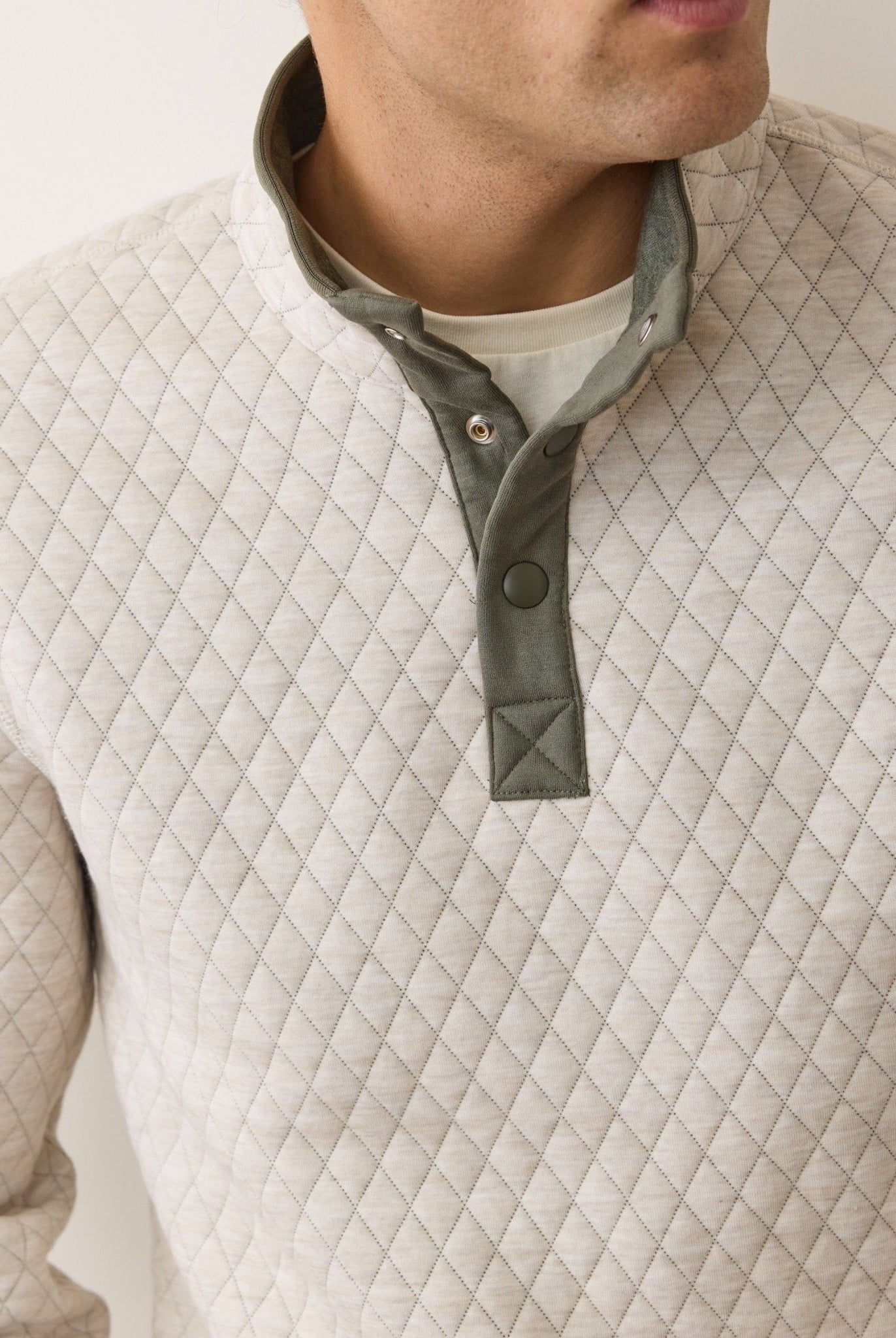 Quilted beige jacket with a green collar on a neutral background
