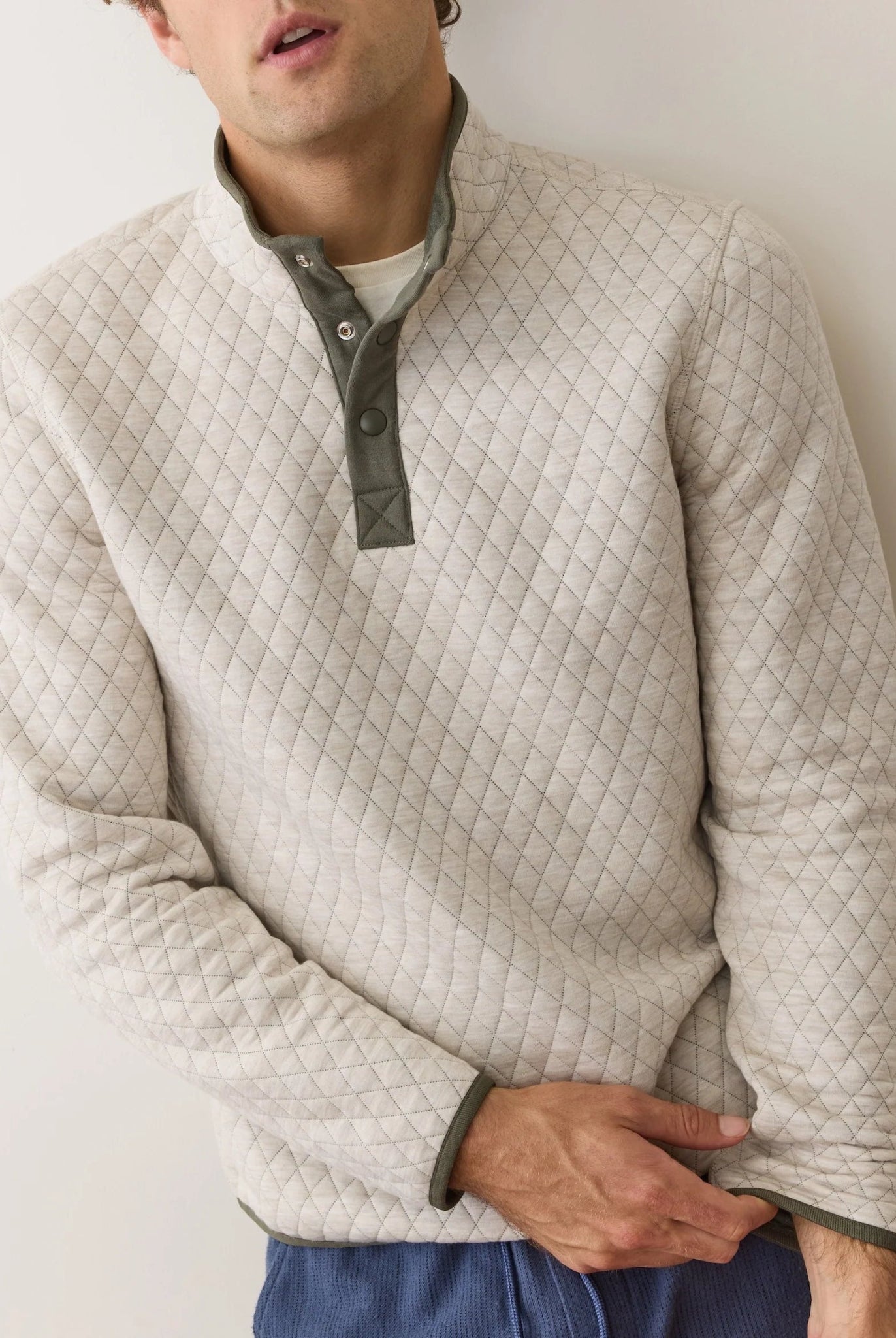 Man wearing a quilted beige pullover against a plain background