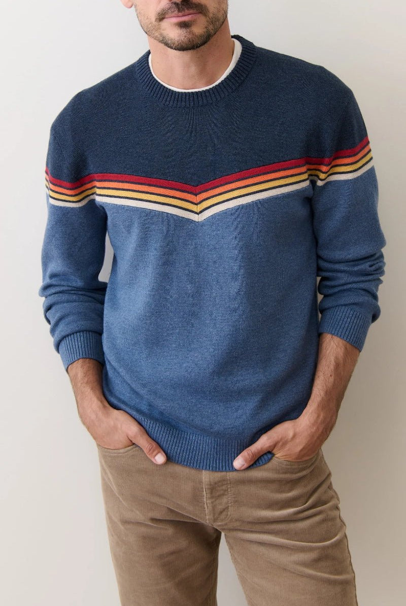 Man wearing a blue sweater with colorful stripes against a plain background