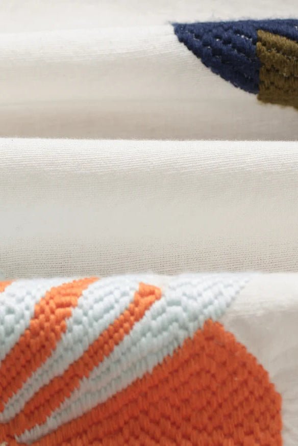 Close-up of a knitted fabric with orange, white, and blue patterns.
