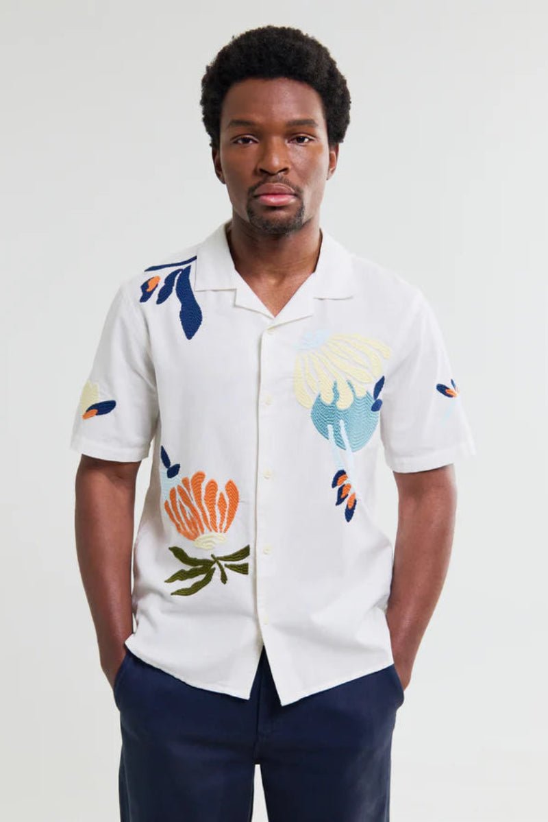 Man wearing a white shirt with colorful abstract patterns on a plain background