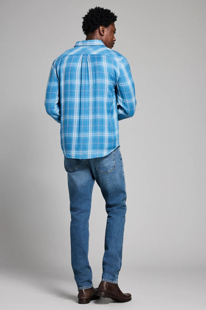 Person wearing a blue plaid shirt and jeans on a gray background