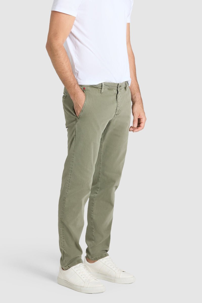 Person wearing olive green pants and a white shirt on a plain background