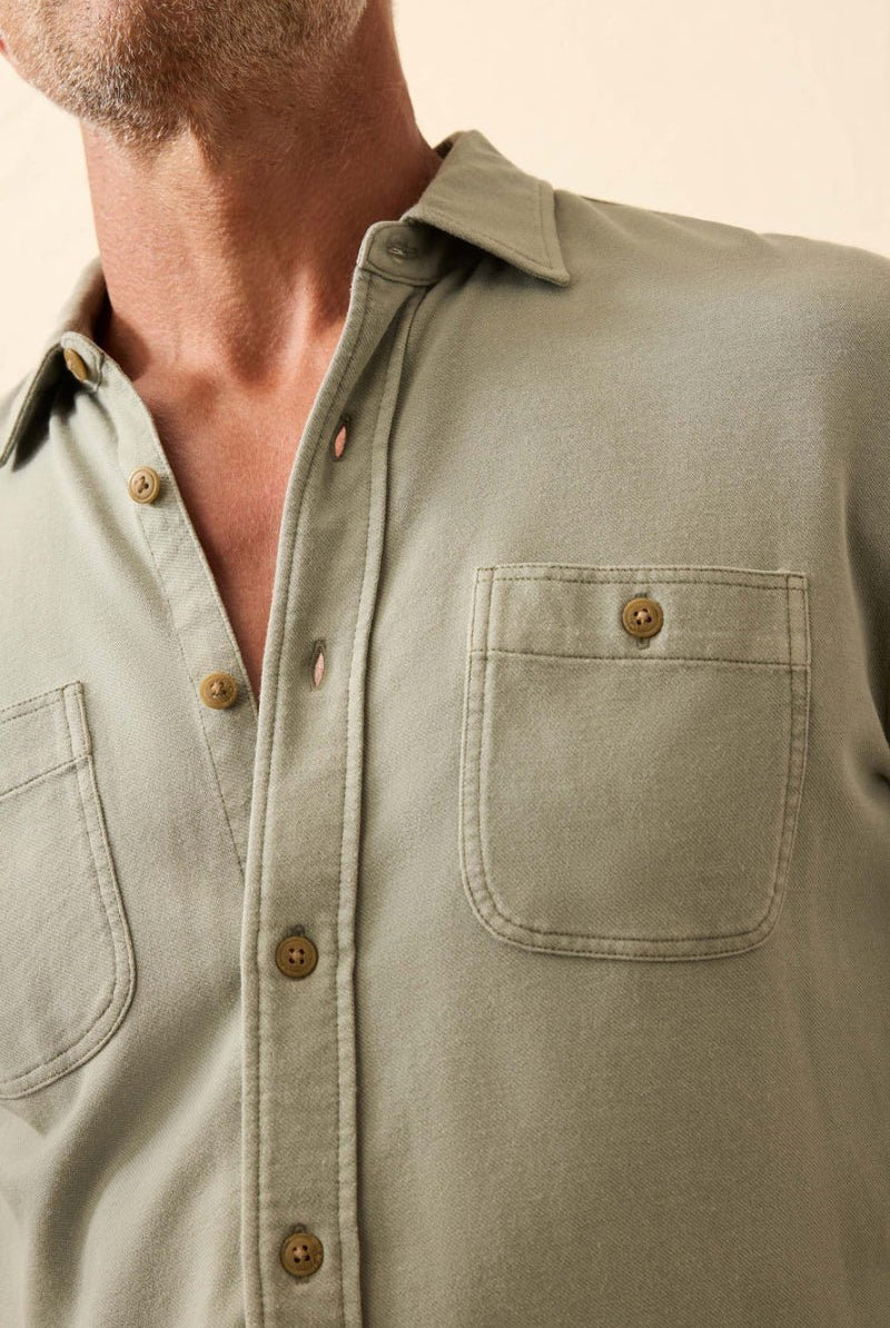 Close-up of a person wearing a light green button-up shirt with a neutral background