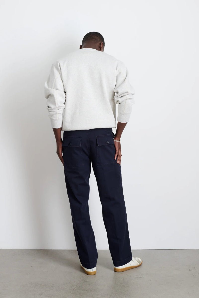 Person wearing a white sweatshirt and dark pants against a plain background