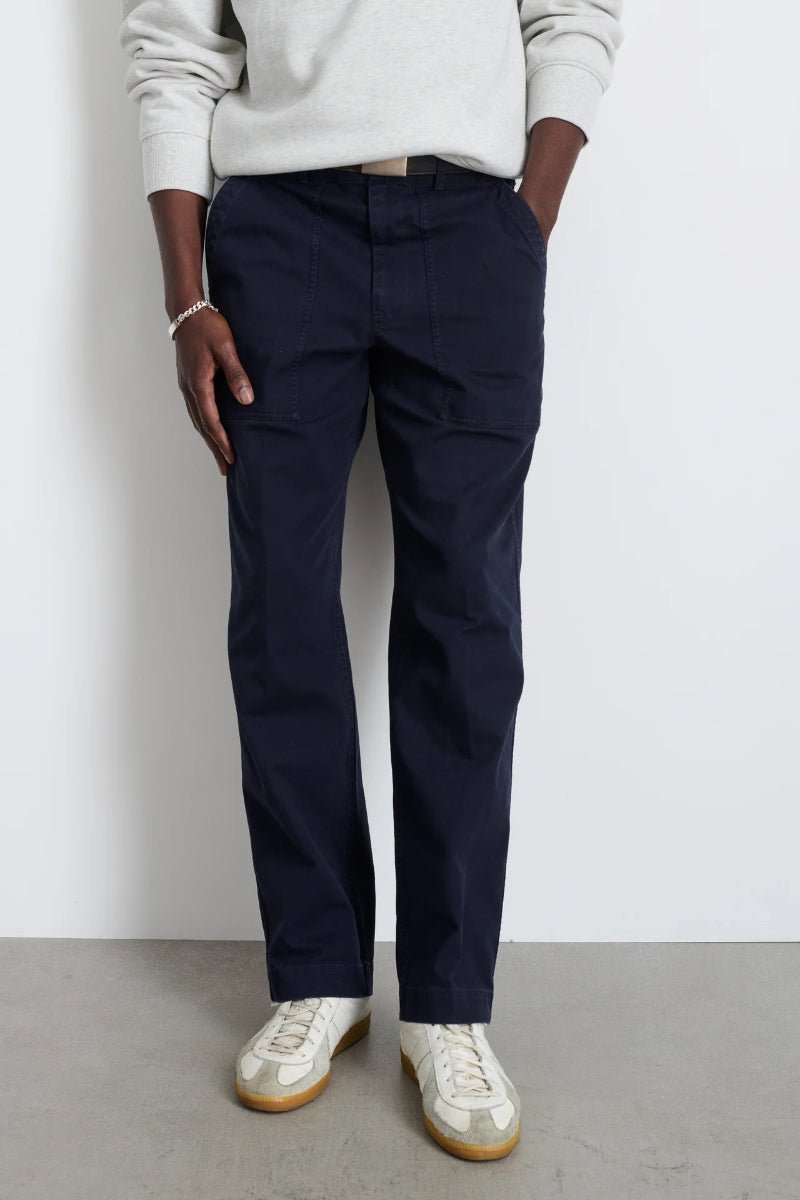 Person wearing navy cargo pants and white shoes against a plain background
