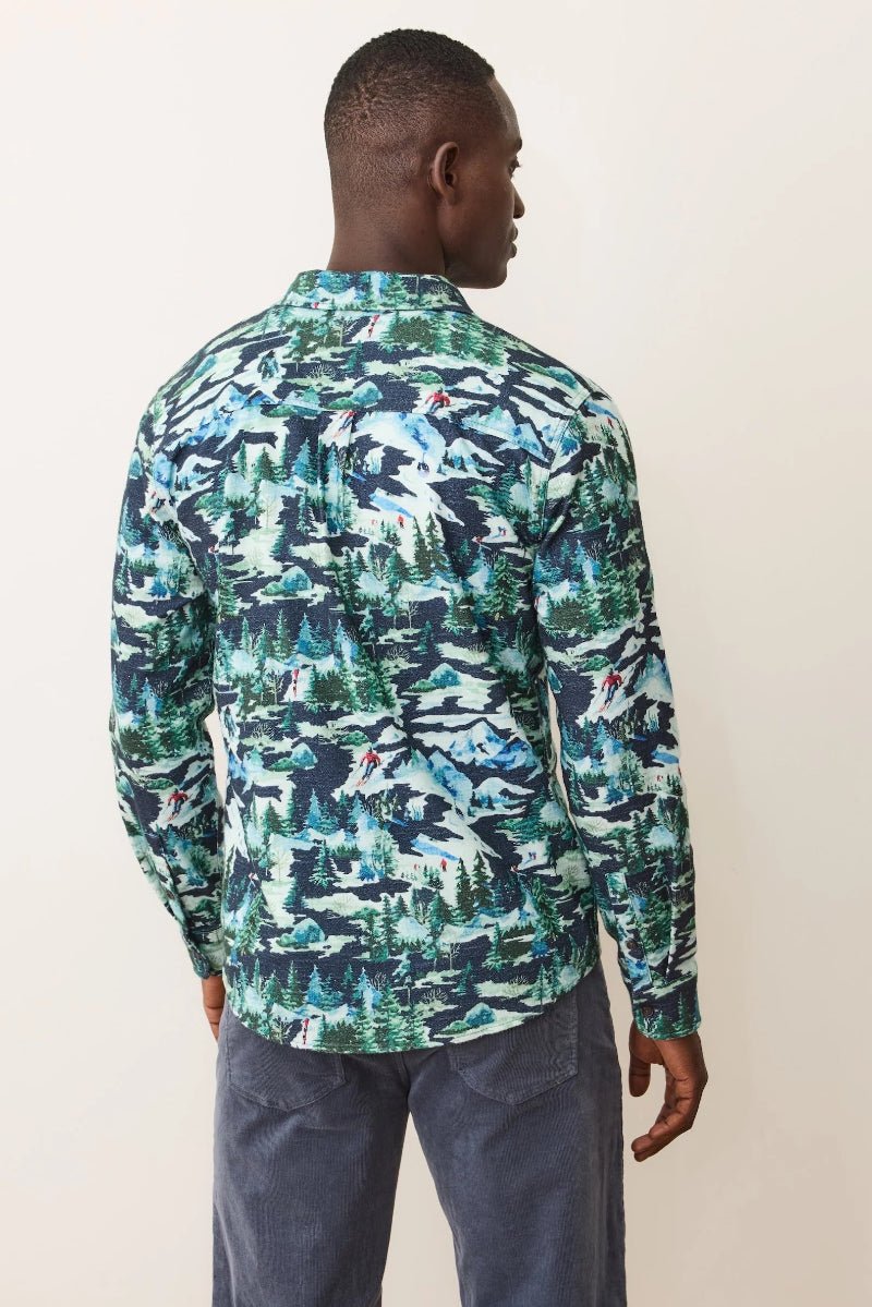 Man wearing a long-sleeve shirt with a green and blue abstract pattern on a plain background