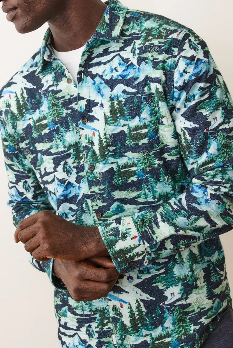 Person wearing a long-sleeve shirt with a nature-themed pattern on a plain background