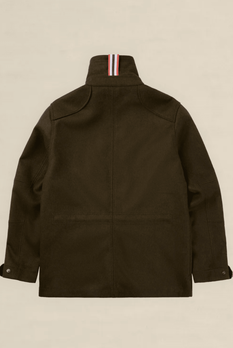 The back view of an olive green utility jacket with a high collar featuring a signature red, white, and blue striped ribbons detail, displayed on a neutral beige background.
