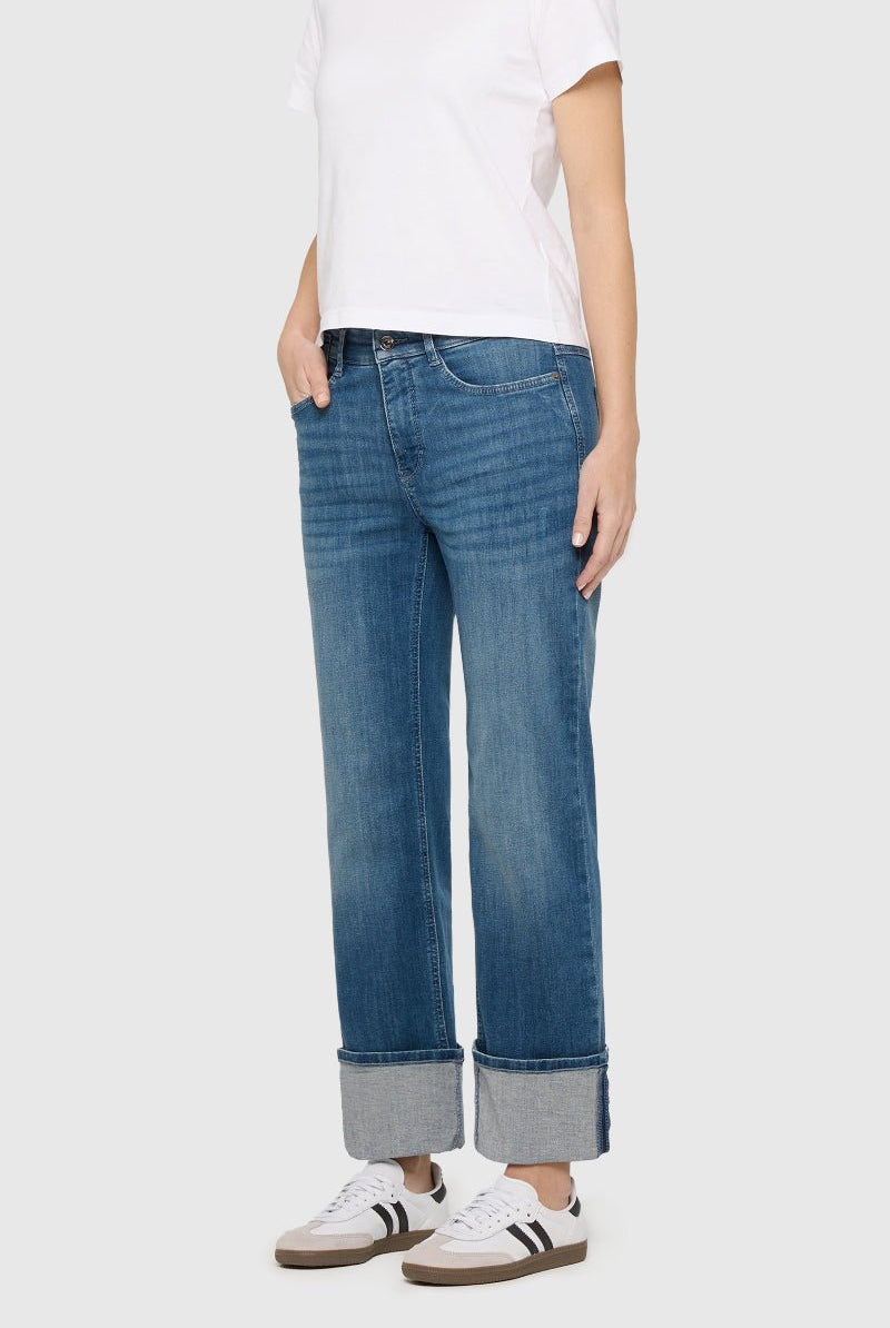 Person wearing blue jeans and a white shirt on a plain background